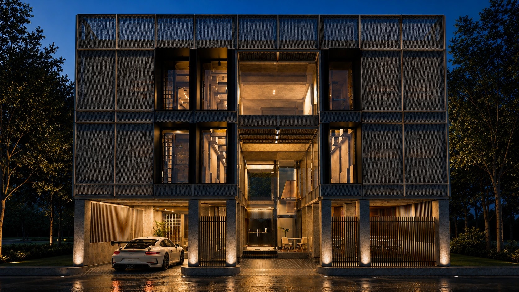 Kobo Hotels at dusk, its lit interiors reading through the expanded metal screen facade above a wet forecourt.